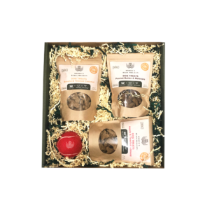 Box of various kinds of Women's Bean Project dog treats, with a Women's Bean Project monogramed tennis ball