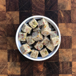 Cubes of women's Bean Project Mango Pomegranate Coconut bites fill a white bowl sitting on the counter.