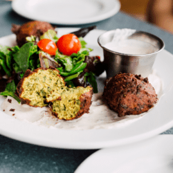 Spicy split pea hushpuppies on a plate with salad and dip.