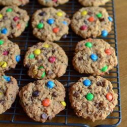 Monster cookies with M&Ms in them sit on a baking rack to cool.