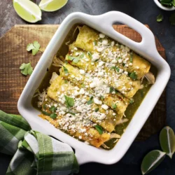 Green chile chicken enchiladas featuring Women's Bean Project Green Chili Spice Blend in a white casserole dish.